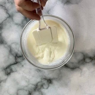 Una persona tiene una spatola sopra una coppetta di gelato.