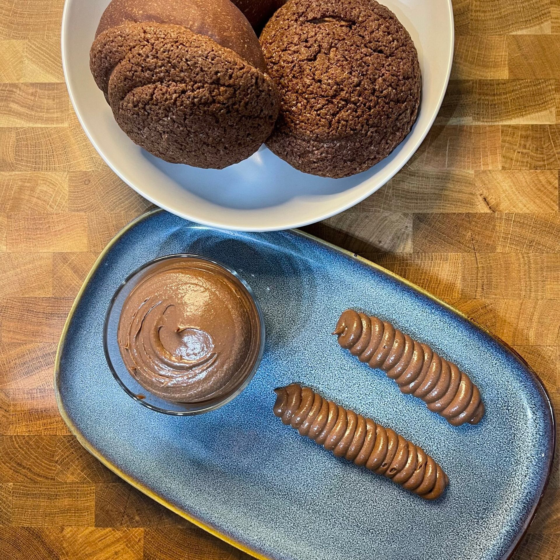 Una ciotola di biscotti al cioccolato e una ciotola di mousse al cioccolato su un piatto blu.