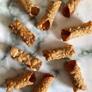 Un mucchio di rotoli di cannoli su una superficie di marmo
