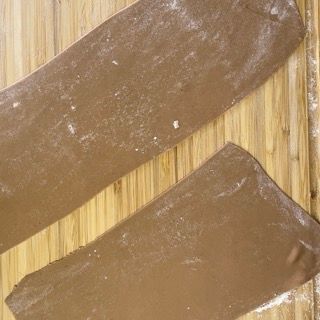 Due pezzi di pasta al cioccolato sono appoggiati su un tagliere di legno.