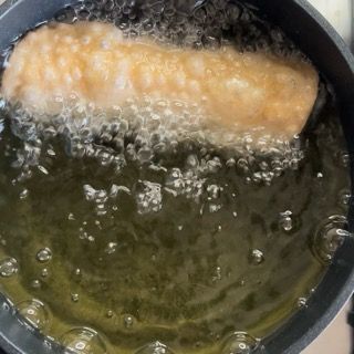 Un pezzo di cibo viene cucinato in una pentola di olio