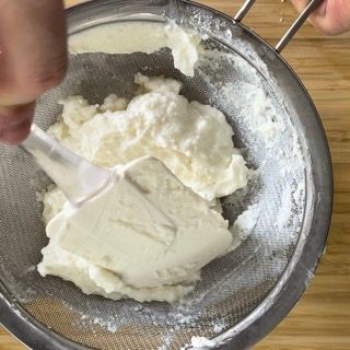 Una persona sta setacciando qualcosa attraverso un colino con un cucchiaio di plastica
