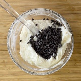 Una ciotola di panna montata con gocce di cioccolato e un cucchiaio dentro