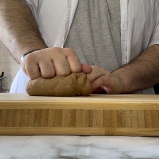 Un uomo sta impastando l'impasto su un tagliere di legno.