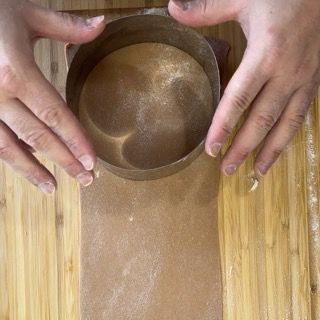 Una persona tiene in mano una ciotola di liquido su un tavolo di legno.