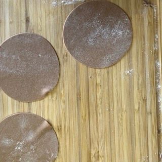 Tre cerchi marroni sono appoggiati su un tagliere di legno.