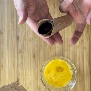 Una persona tiene in mano un tubo accanto a una ciotola piena di liquido giallo.
