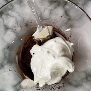 La panna montata viene mescolata in un bicchiere con un cucchiaio di plastica.