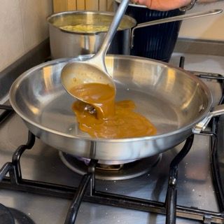 Una persona sta versando la salsa in una padella sul fornello
