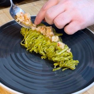 Un piatto nero con sopra tagliatelle e gamberi