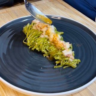 Un piatto nero con sopra tagliatelle e gamberi