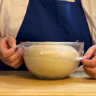 Una persona sta avvolgendo una ciotola di pasta in pellicola trasparente
