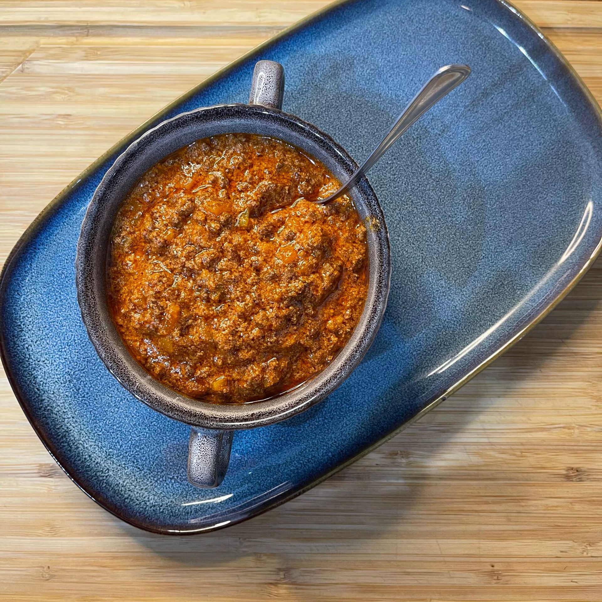Ragù alla bolognese tradizionale che sobbolle lentamente in una pentola di coccio per una cottura lunga.