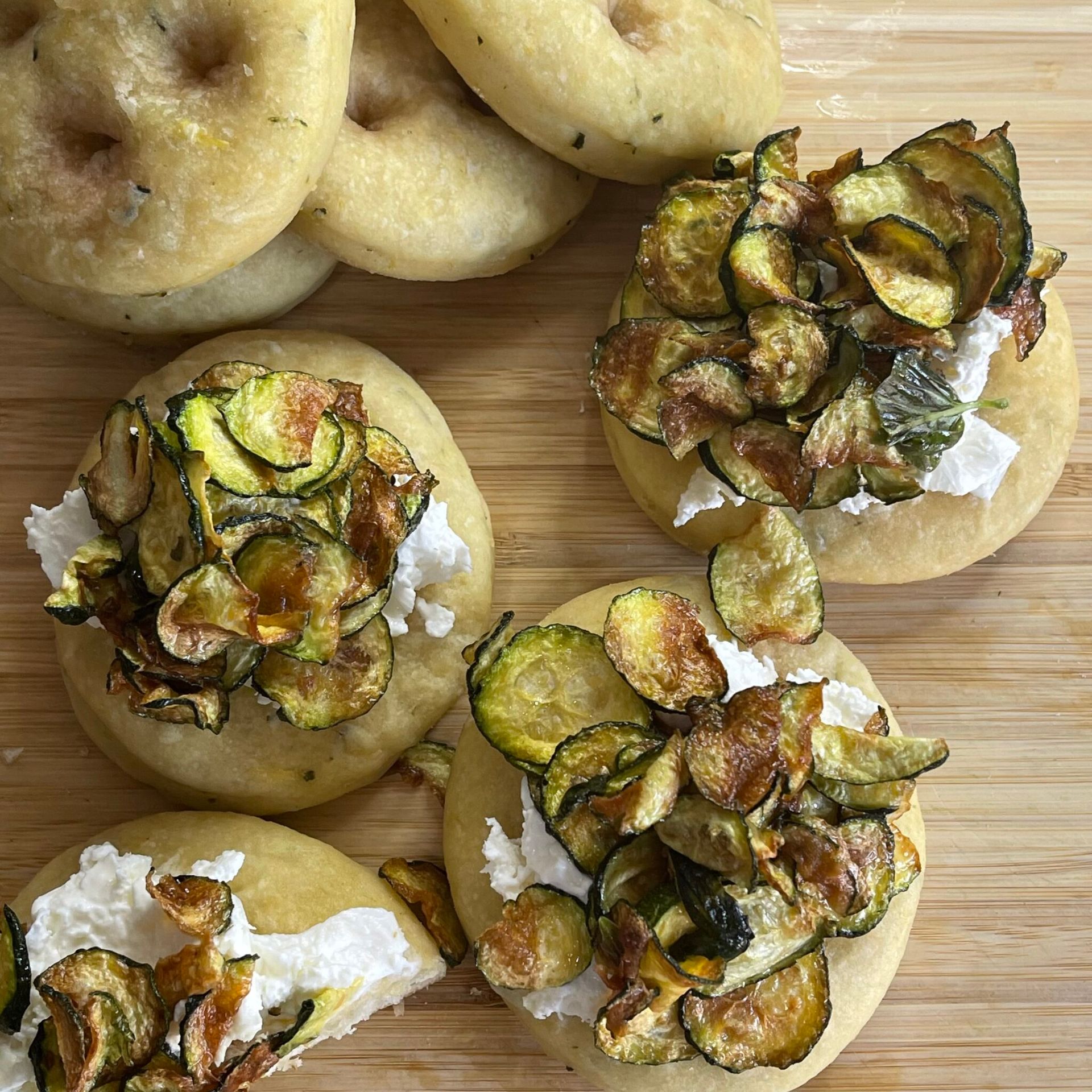Un tagliere di legno con sopra un mucchio di cibo con zucchine e formaggio.