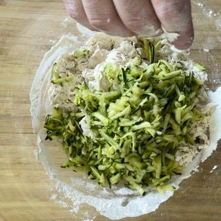Una persona sta mescolando zucchine e farina in una ciotola