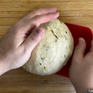 Una persona tiene in mano una palla di pasta su un tagliere