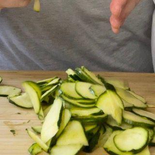 Una persona sta tagliando le zucchine su un tagliere