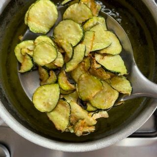 Una pentola di chips di zucchine con un cucchiaio dentro