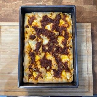 Una pizza in padella su un tagliere di legno