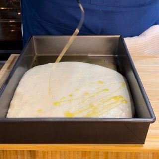 Una persona sta versando l'olio in una padella di pasta