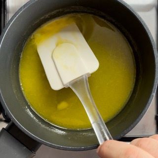 Una persona sta mescolando una pentola di liquido giallo con una spatola