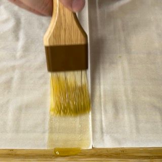 Una persona sta usando un pennello per stendere un liquido su un pezzo di carta.