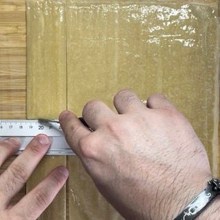 Una persona sta misurando un pezzo di carta con un righello