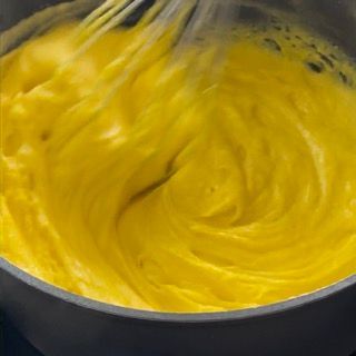 Primo piano di una ciotola di salsa gialla con una frusta dentro.