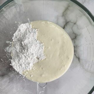 Un frullatore pieno di un liquido bianco e zucchero a velo.