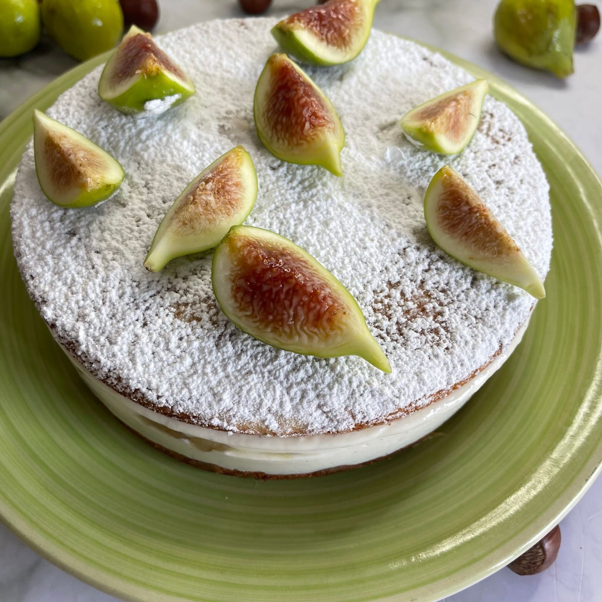 Una torta con zucchero a velo e fichi su un piatto verde
