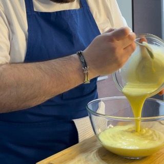 Un uomo che versa un liquido giallo in una ciotola di vetro