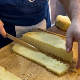 Una persona sta tagliando una fetta di torta su un tagliere