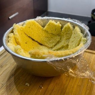 Una ciotola di cibo avvolta nella plastica è appoggiata su un tagliere di legno