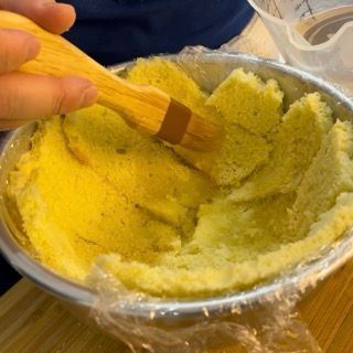 Una persona tiene una spazzola di legno sopra una ciotola di cibo