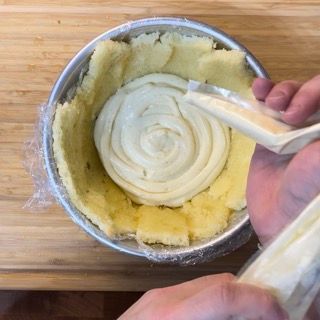 Una persona sta versando la panna in una ciotola di purè di patate