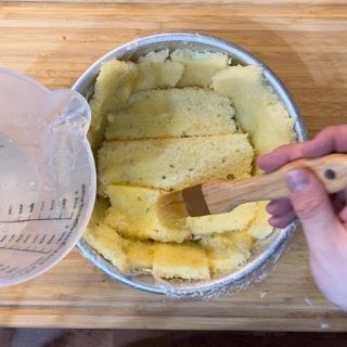 Una persona tiene una spazzola di legno sopra una ciotola di purè di patate