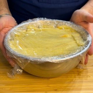 Una persona tiene in mano una ciotola di cibo avvolta nella pellicola trasparente.
