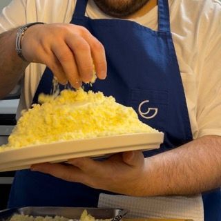 Un uomo con un grembiule blu tiene in mano un piatto di cibo