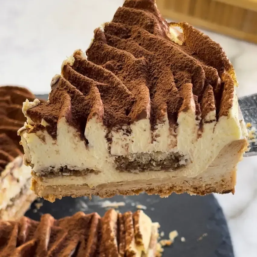 Fetta di crostata tiramisù moderna che mostra gli strati di frolla, savoiardi al caffè e crema al mascarpone.
