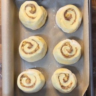 Apple cinnamon rolls disposti sulla teglia e raddoppiati di volume dopo 2 ore.