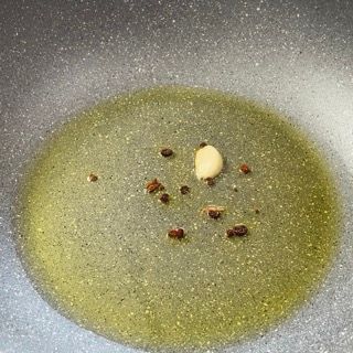 Aglio e peperoncino in padella con l'acqua delle vongole filtrata che bolle.
