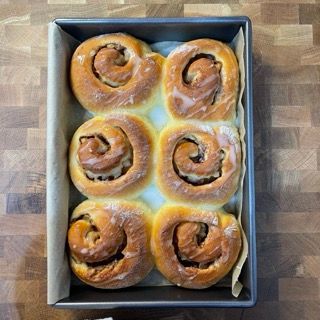 Apple Cinnamon Rolls (girelle alle mele) appena sfornati in una teglia, coperti da una glassa bianca.