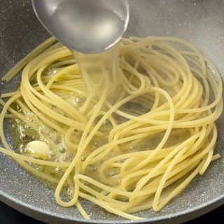 Spaghetti risottati in padella con l'acqua delle vongole.