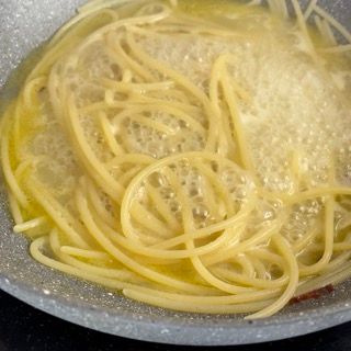 Spaghetti risottati in padella con l'acqua delle vongole.