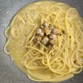 Vongole sgusciate aggiunte agli spaghetti a fine cottura.