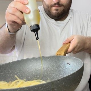 Mantecatura finale degli spaghetti alle vongole con olio a crudo e prezzemolo.