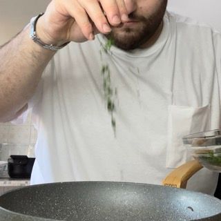 Mantecatura finale degli spaghetti alle vongole con olio a crudo e prezzemolo.