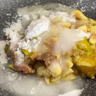Primo piano di una padella piena di cibo e zucchero a velo.