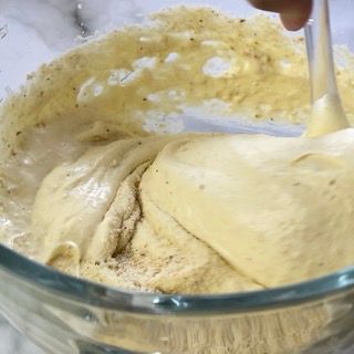 Una persona sta mescolando un impasto in una ciotola di vetro con un cucchiaio.