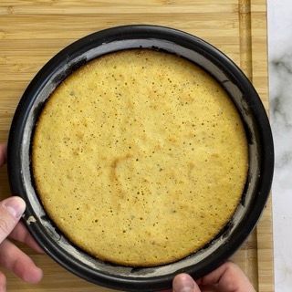 Una persona tiene in mano una torta in una teglia su un tagliere.
